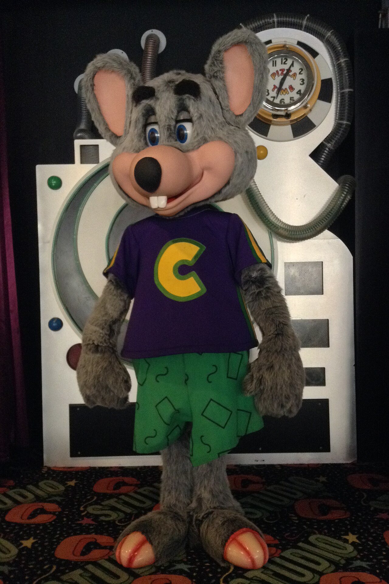 A Chuck E. Cheese animatronic character on a restaurant stage
