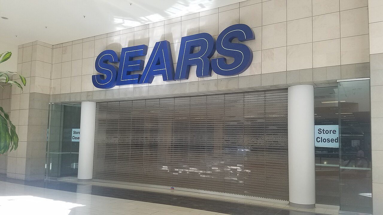 A closed Sears store inside Hanes Mall in Winston-Salem, North Carolina, its sign still mounted above the shuttered mall entrance