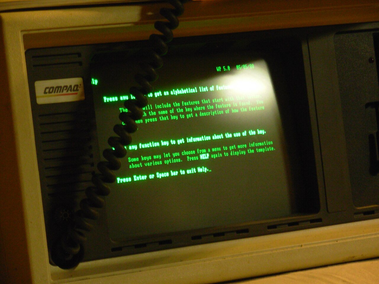 A 1983 Compaq Portable computer with its built-in green monochrome screen running WordPerfect