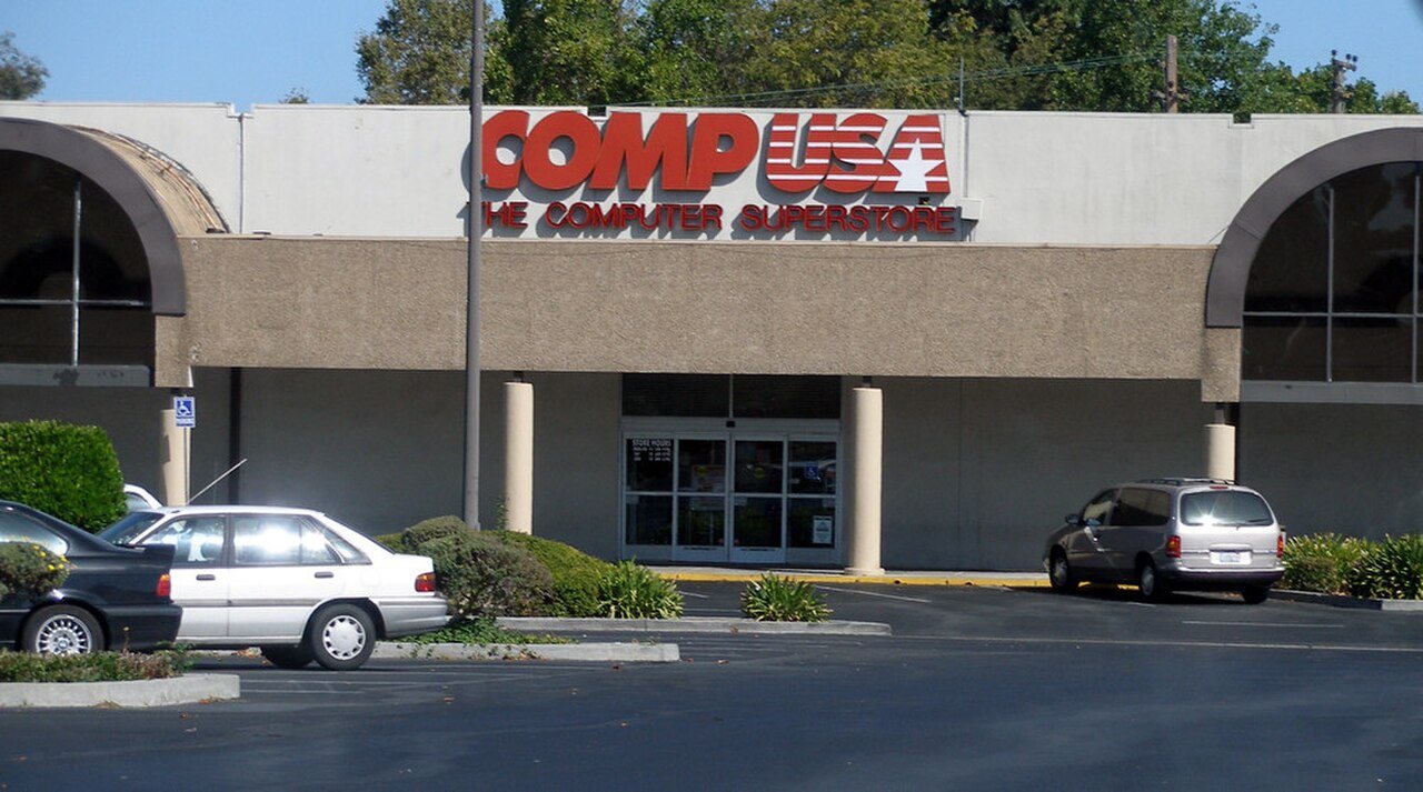 The exterior of a CompUSA computer superstore with its red and blue sign above the entrance