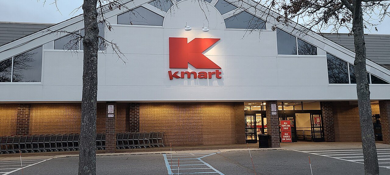 The red Kmart sign above the entrance of the Bridgehampton, New York store, with shopping carts lined up outside and sale signs on the doors
