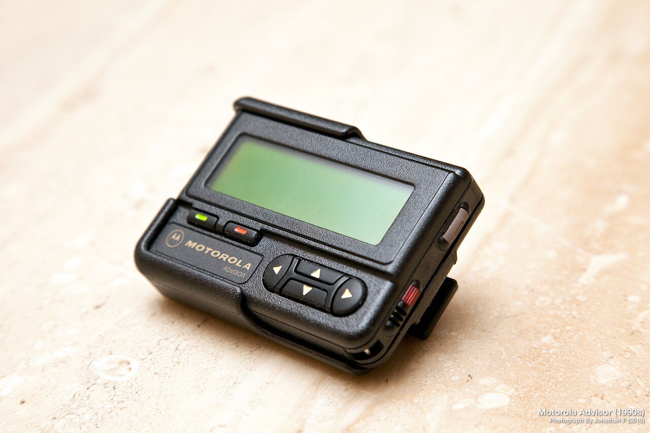A 1990s alphanumeric pager with a small LCD screen and a belt clip