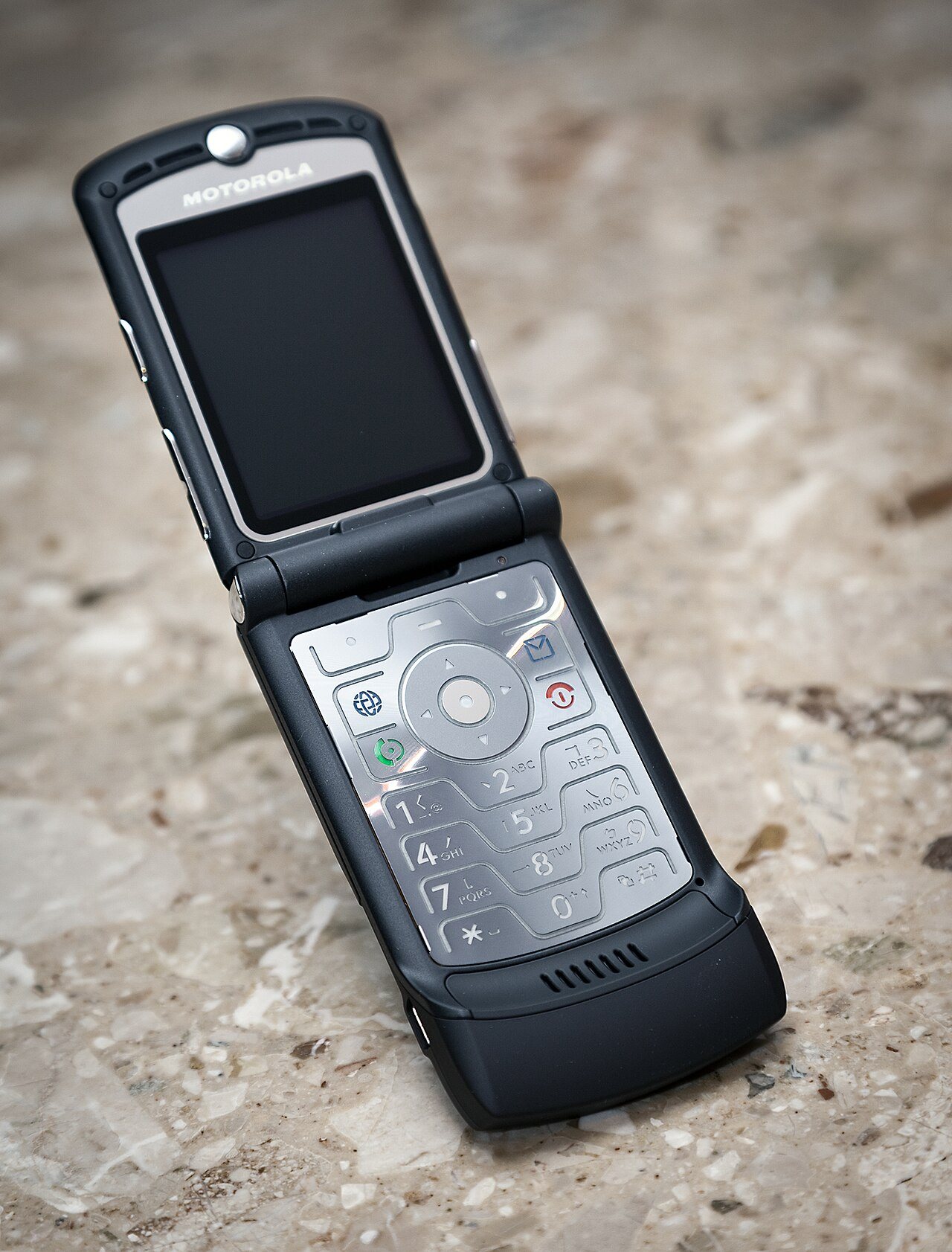 A black Motorola Razr V3 flip phone, closed, showing its slim metallic body