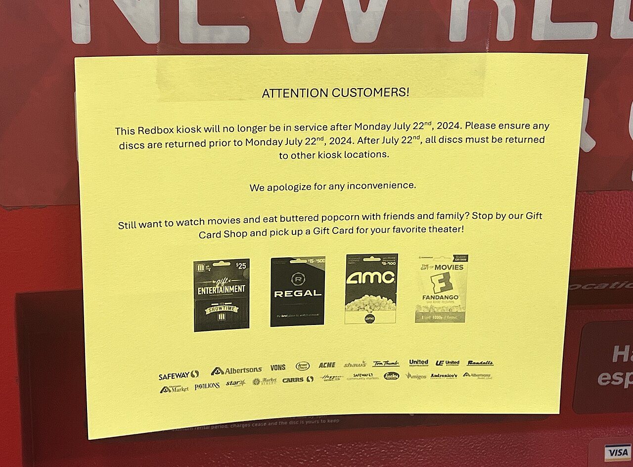 A red Redbox DVD rental kiosk standing outside a store