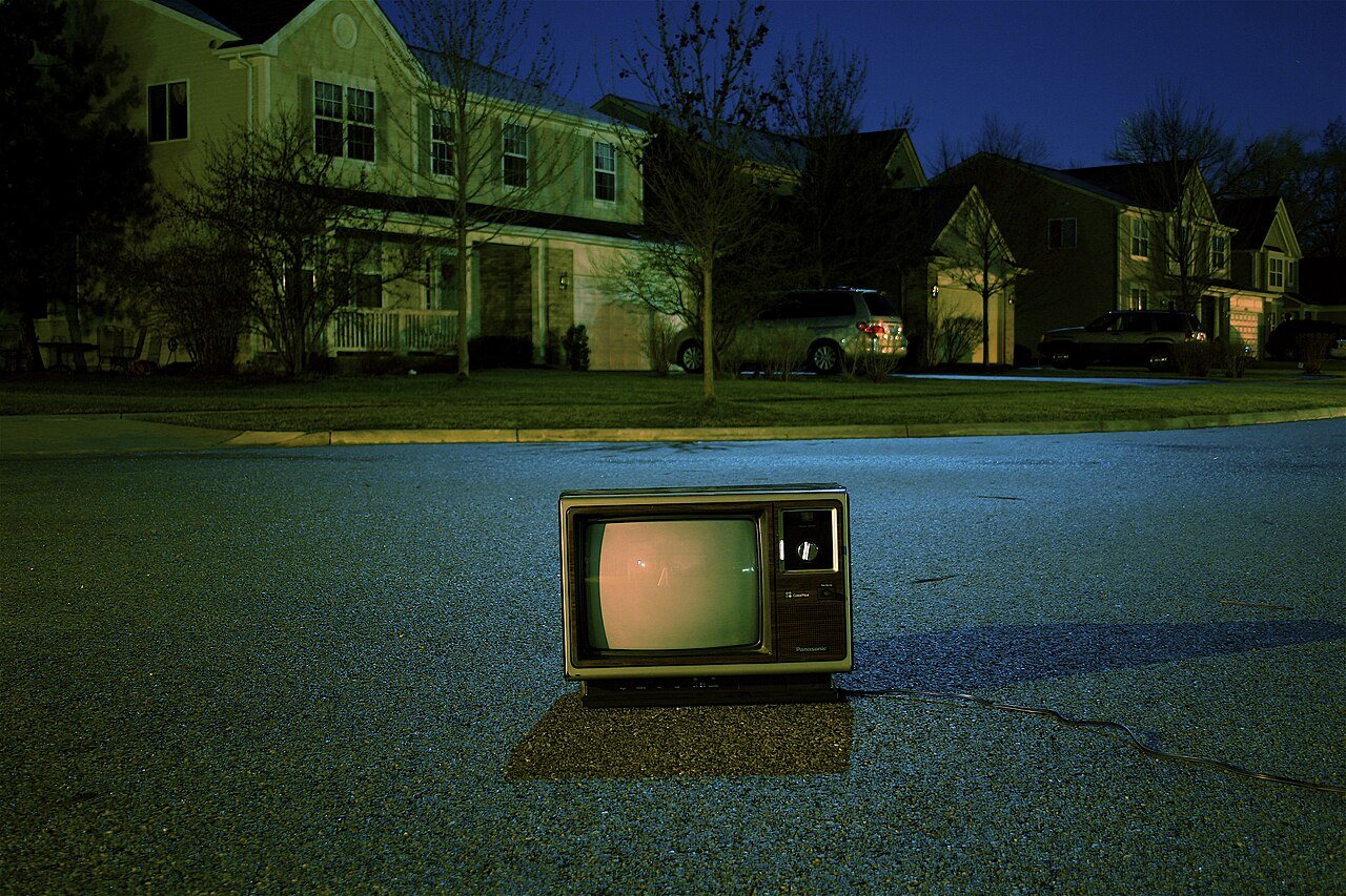 An old television set standing on a suburban road at dusk